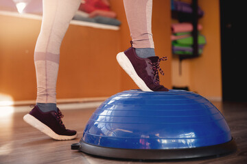Close-up of legs in sports shoes perform exercises on bosu balance ball