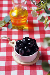 black olives and olive oil on a checkered tablecloth italy style. High quality photo
