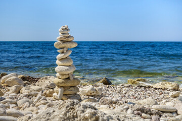 Fototapeta na wymiar Symbolic pyramid made from coastal stones nearby edge of sea or ocean