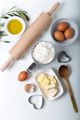 Food ingredients for bakery or homemade bread or pasta, olive oil, flour, eggs on white background. Top view of dough and baking ingredients isolated on white.