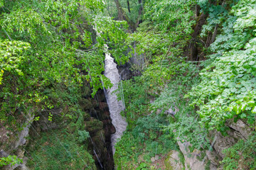 Heavy downpour on the abyss and river among the Caucasus Mountains. Green vegetation and shrubs on...