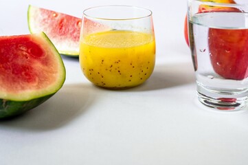 Sliced melony, glass of fruit smoothie and glass of water on white background.