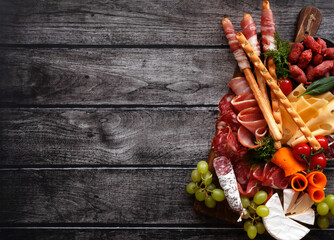 Antipasti, a traditional Italian snack on a dark wooden table. Sliced meat. Top view. Copy the space. - 417934108