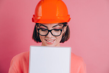 Smiling woman worker builder hold white sign board blank against pink background. Building helmet.