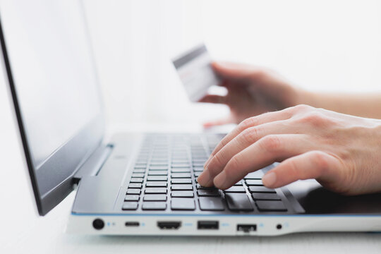 Woman's hands holding credit bank card and using laptop computer at home Online shopping concept