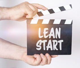On a white background, a man holds a clapperboard in his hands on which it is written - LEAN START