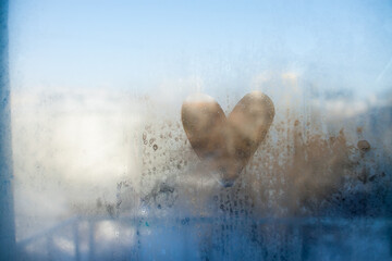 heart painted on misted glass. View from the window to the winter sunny city. High quality photo