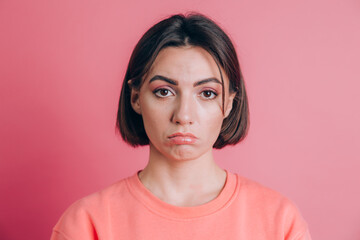 Portrait of sad upset young woman with bright makeup on pink background