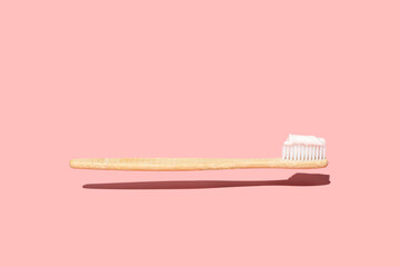 Levitating Wood Toothbrush with Toothpaste On Pink Background. Trendy Zero Waste Wooden Toothbrush...