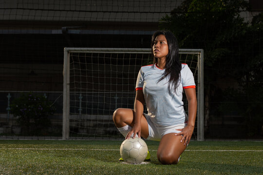 Portrait of latin female soccer player with the ball in the field. Female football player concept