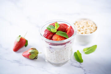 Oatmeal porridge with milk and fresh strawberries in a glass
