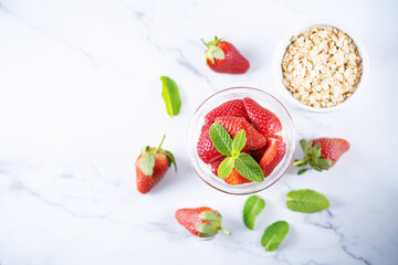 Oatmeal porridge with milk and fresh strawberries in a glass