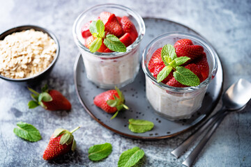 Oatmeal porridge with milk and fresh strawberries in a glass