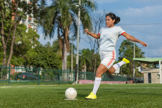 Full length portrait of a latin female soccer player about to kick the ball. Female football player concept