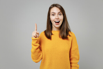 Young pretty attractive cute smart intelligent insighted woman 20s wearing casual knitted yellow sweater holding index finger up with great new idea isolated on grey color background studio portrait.