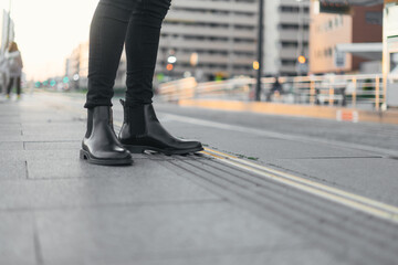 Feet of a businessman in a mask waiting for the train at the station