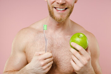 Cropped image of smiling bearded naked young man 20s perfect skin hold toothbrush green fresh apple...