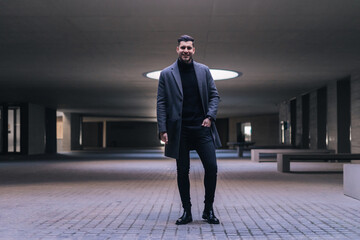 Handsome young businessman standing smiling.