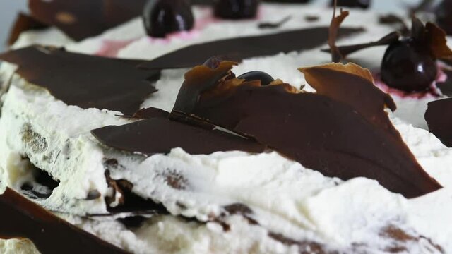 una bella torta foresta nera con le foglie di cioccolato immerse nella bianca copertura di panna e amarene, una vista ravvicinata di una torta 