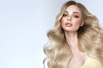 Fototapeta premium Beautiful blond girl with a perfectly curls hair, and classic make-up. Beauty face and hair.