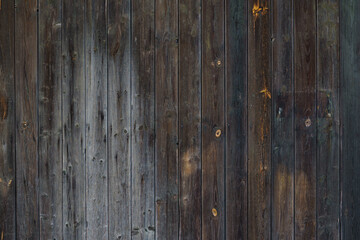 Naklejka premium Fragment of a dark wooden fence. The boards fit tightly to each other.