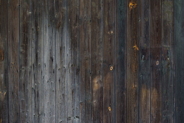 Fragment of a dark wooden fence. The boards fit tightly to each other.