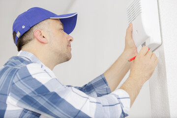 male technician installing alarm system indoors