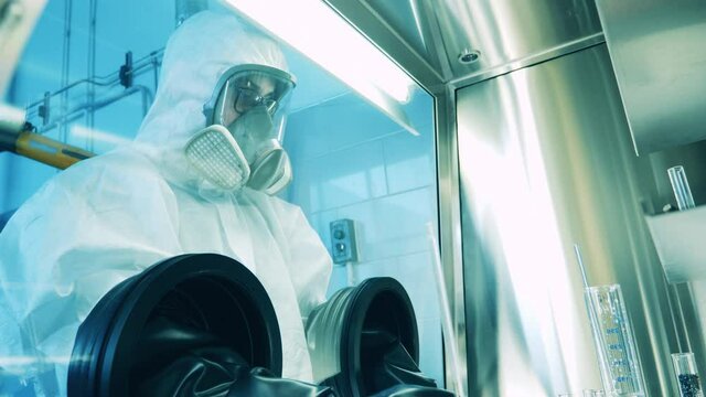 Lab worker in a hazmat suit is analyzing probes in a laboratory cabinet
