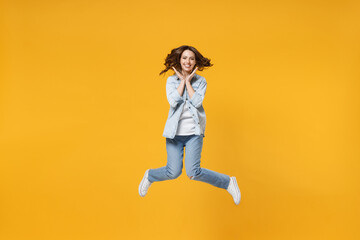 Full length of young overjoyed surprised excited shocked fun student happy woman 20s wearing denim shirt white t-shirt spread hands celebrating jump high isolated on yellow background studio portrait