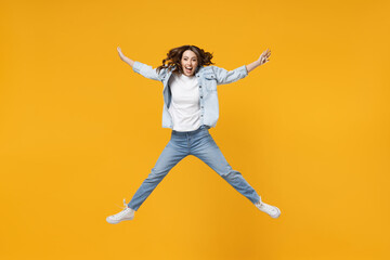 Fototapeta na wymiar Full length of young overjoyed excited fun expressive student happy woman 20s wearing denim shirt white t-shirt with outstretched hands legs jump high isolated on yellow background studio portrait