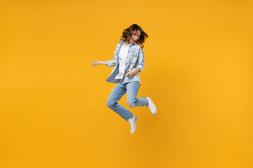 Fototapeta na wymiar Full length of young overjoyed excited fun expressive student happy woman 20s wearing casual denim shirt white t-shirt playing guitar jump high isolated on yellow color background studio portrait