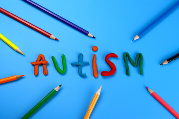 autism word from made of colored modeling clay or plasticine on a blue background