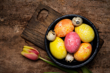 Colorful tulips and painted Easter eggs on a wooden table