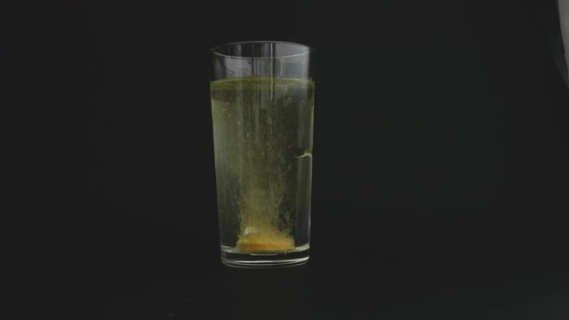 A water-soluble vitamin C tablet is dipped into the water. Oops hiss in the water. The water turns yellow.
