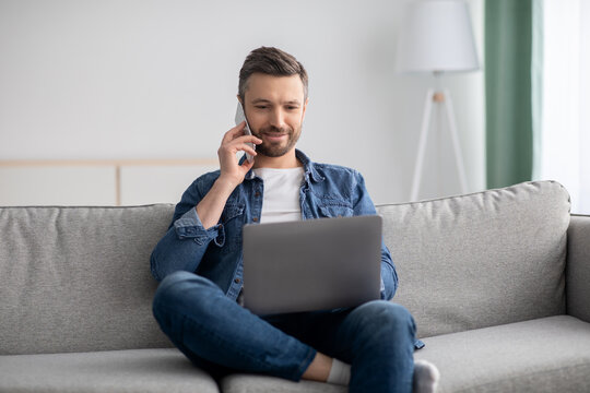 Positive middle-aged man with laptop talking on smartphone