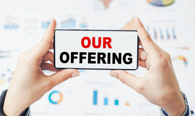 Notebook with OUR OFFERING word with office tools on white table. business conceptual