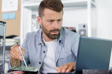 man with a screwdriver is repairing computer equipment