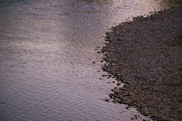 River bank during sunset reflects purple light