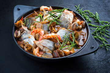 Modern style traditional Spanish seafood zarzuela de pescado with fish, king prawns and venus clams...