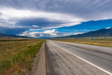 Fototapeta na wymiar Scenic view of an empty road with mountains on the background, in the State of Colorado, USA; Concept for travel and road trip in the USA