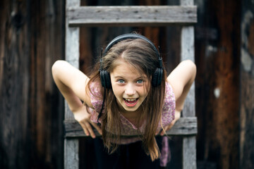 Naughty litle girl with headphones outdoors portrait.