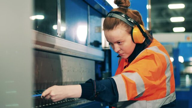 Female professional bends a metal part using a special machine