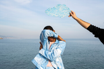 Male holding cloud cut out on young man head standing and covering face against sky