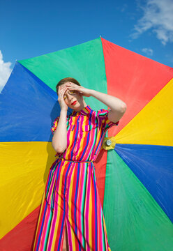 Carefree woman against colorful beach umbrella on sunny day