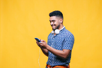 Smiling man using mobile phone by yellow background