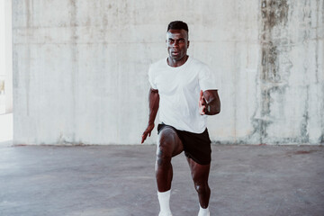 Active male athlete running against white wall