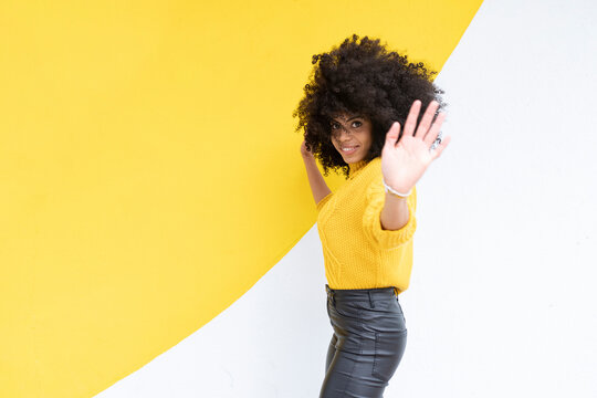 Young woman dancing while standing against multi colored wall