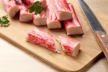 Appetizing crab sticks on wooden cutting board. Selective focus on cut crab stick