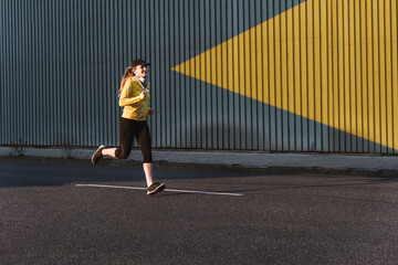 Young woman jogging along asphalt street