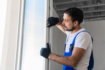Bearded builder in gloves inspects the window frame